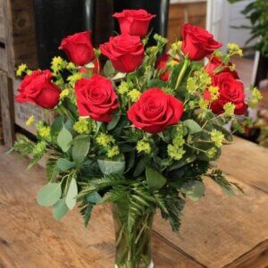 one dozen roses arranged with premium greens in glass vase