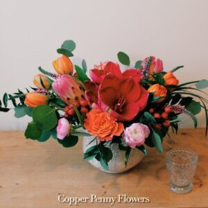 Dress Up flower arrangement featuring rouge amaryllis, orange tulips, and pink ranunculus