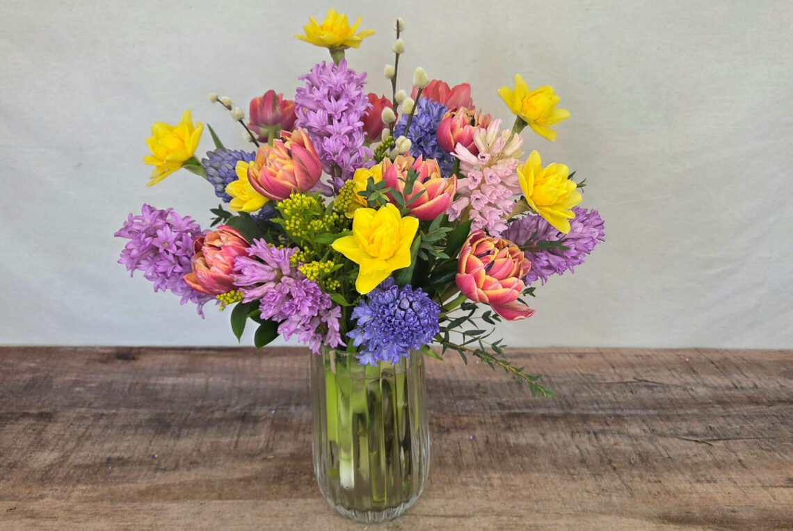 All About Spring is a mixed arrangement with daffodils, hyacinths, and tulips in a glass vase
