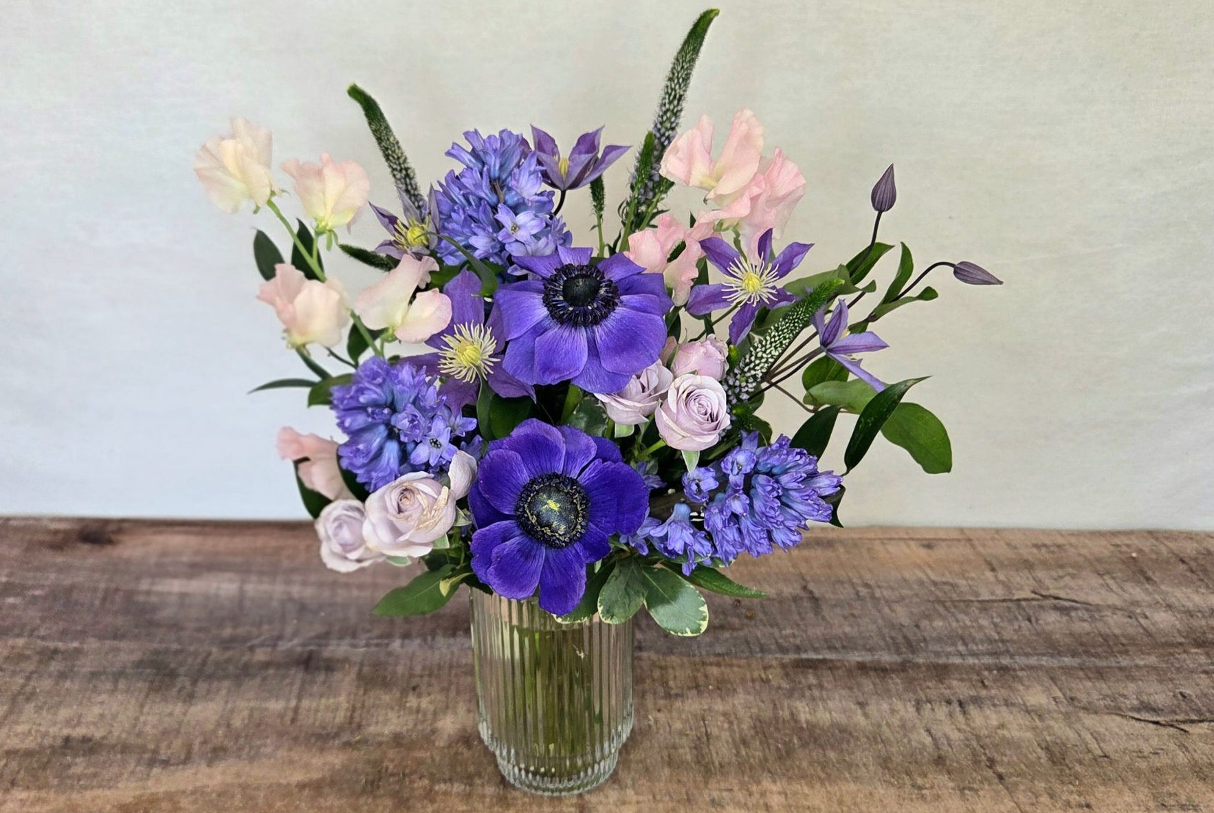 Blushing Plum is a purple and pink flower arrangement featuring purple anemones in a glass vase