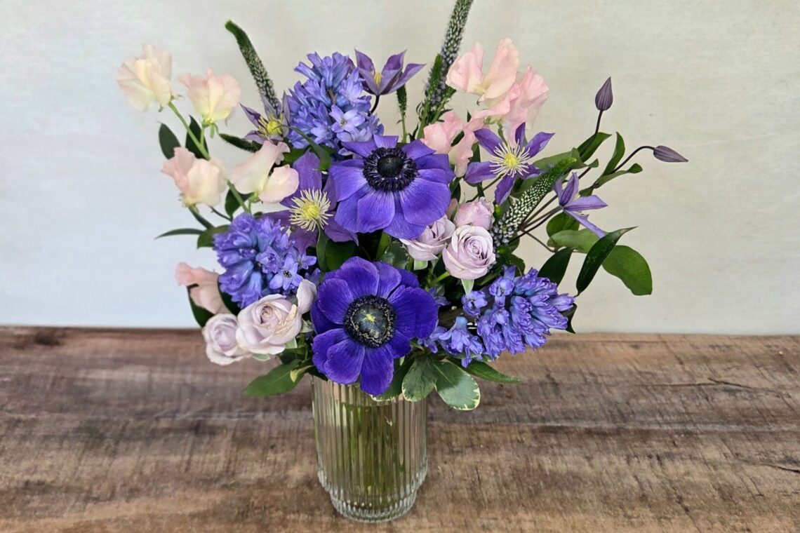 Blushing Plum is a purple and pink flower arrangement featuring purple anemones in a glass vase