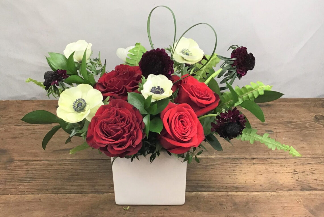Heart 2 Heart arrangement features red and white blooms in a white ceramic container with a lily grass heart