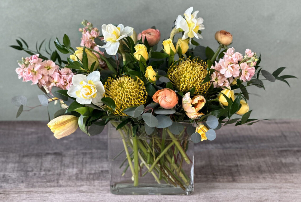 Jo's Indulgence is a peach, white, and yellow flower arrangement featuring tulips and protea