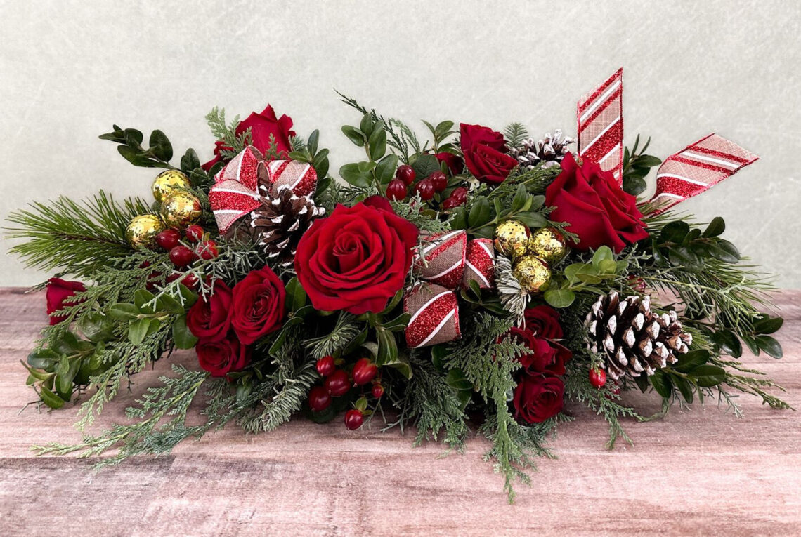 Sweet Christmas is a centerpiece featuring red blooms and evergreens with peppermint striped ribbon